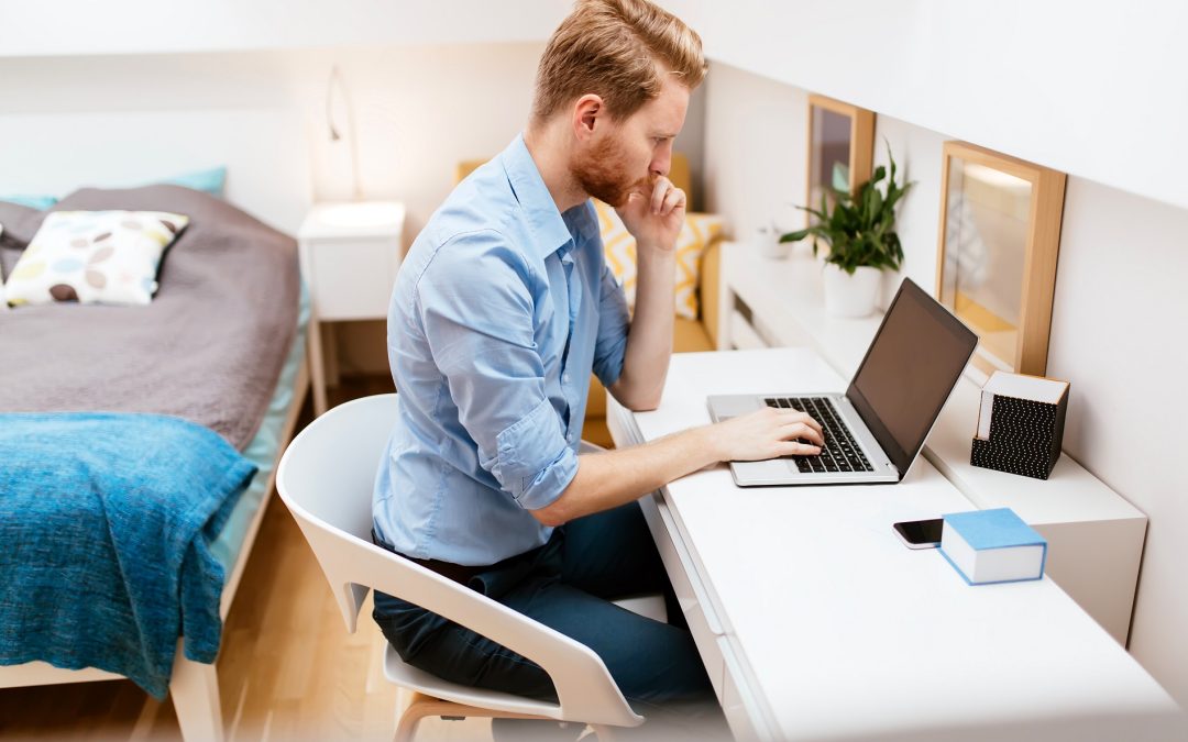 A man sitting at his desk using a laptop.