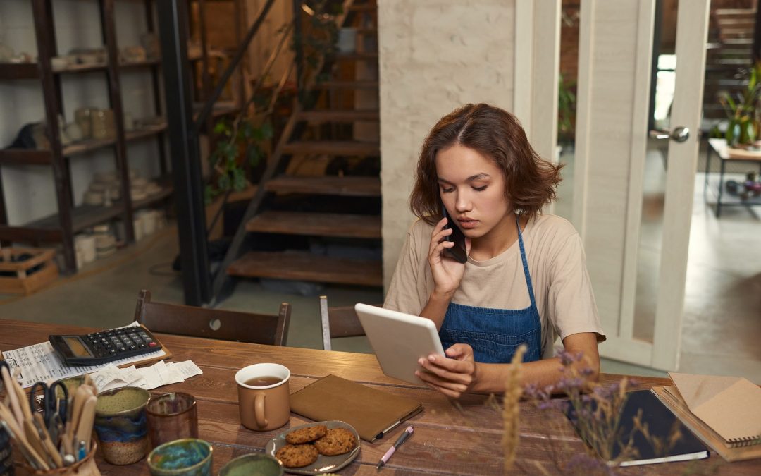 A woman sitting at a table with a tablet and phone.