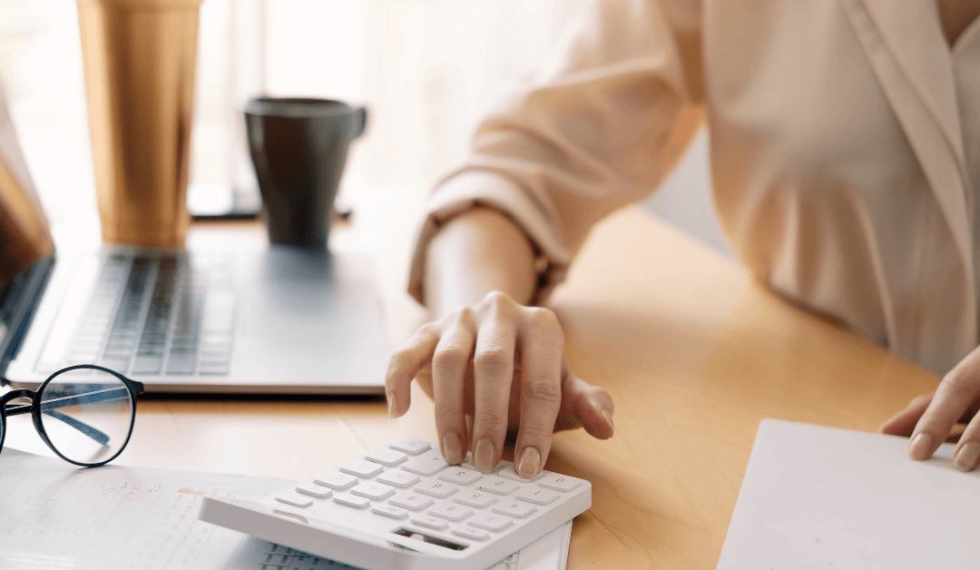 A person using a calculator on top of a desk.