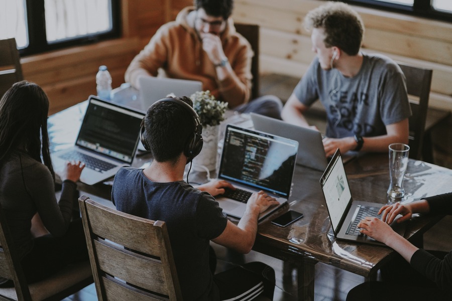 A group of people sitting at tables with laptops.